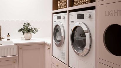 pink laundry room with washing machines and shelving