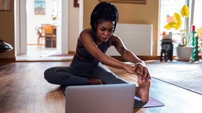 2020 fitness trends: humming yoga Woman at laptop stretching