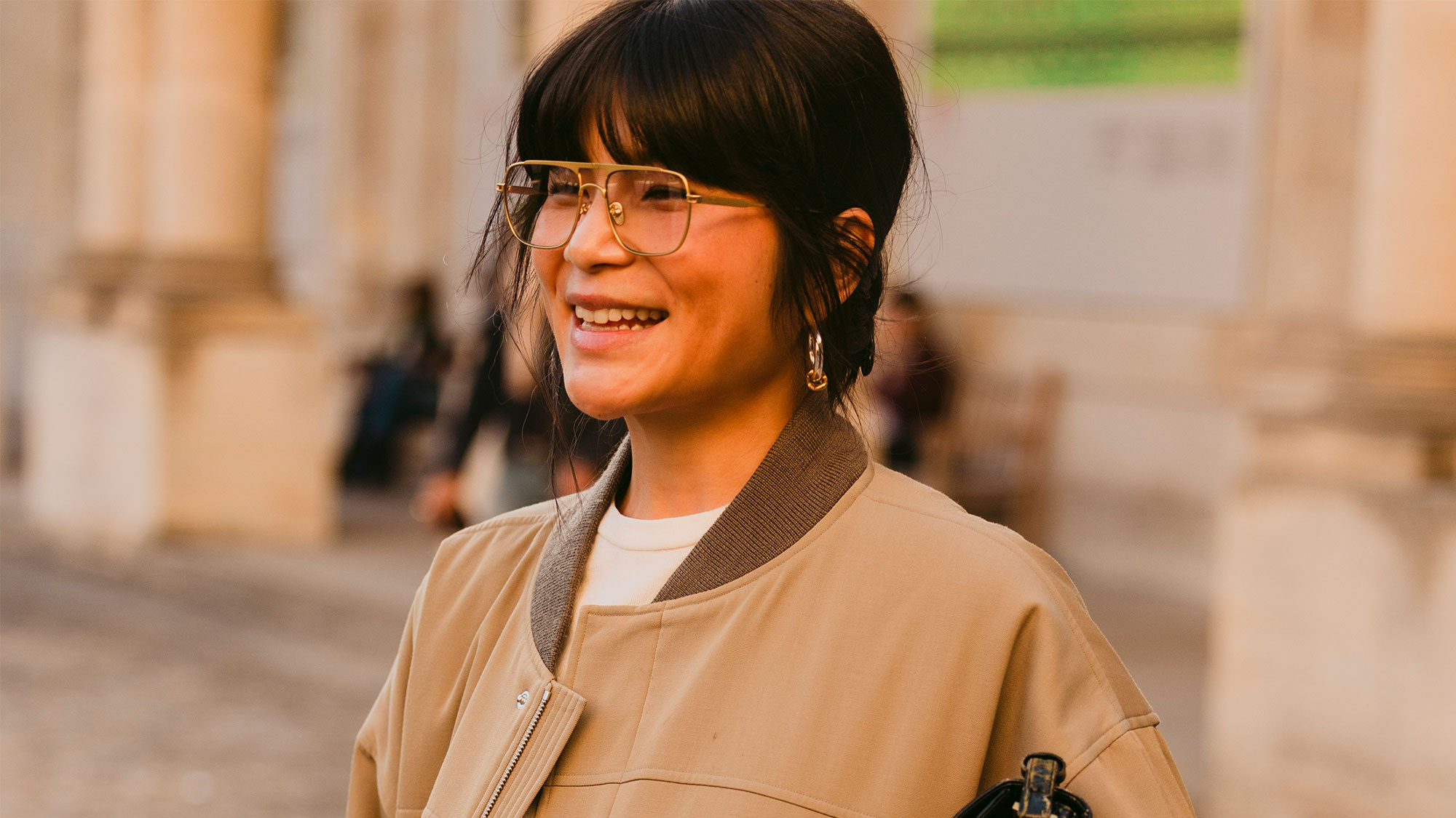 Woman wearing wire-frame glasses and a tan jacket.