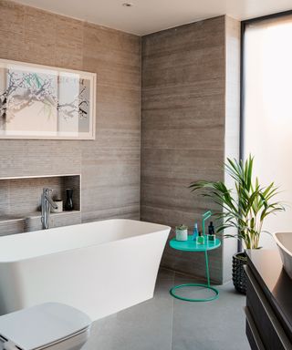 Space-boosting large grey tiles on a small bathroom wall and floor with white bath tub.