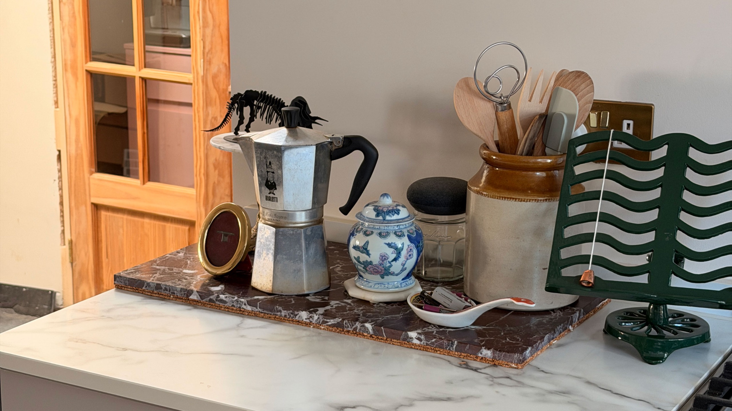 Kitchen worktop with marble tray holding coffee pot, decor and jar of utensils