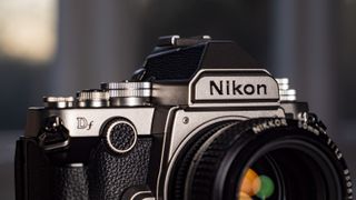 Nikon Df DSLR camera on a wooden surface by large window, with dusk light