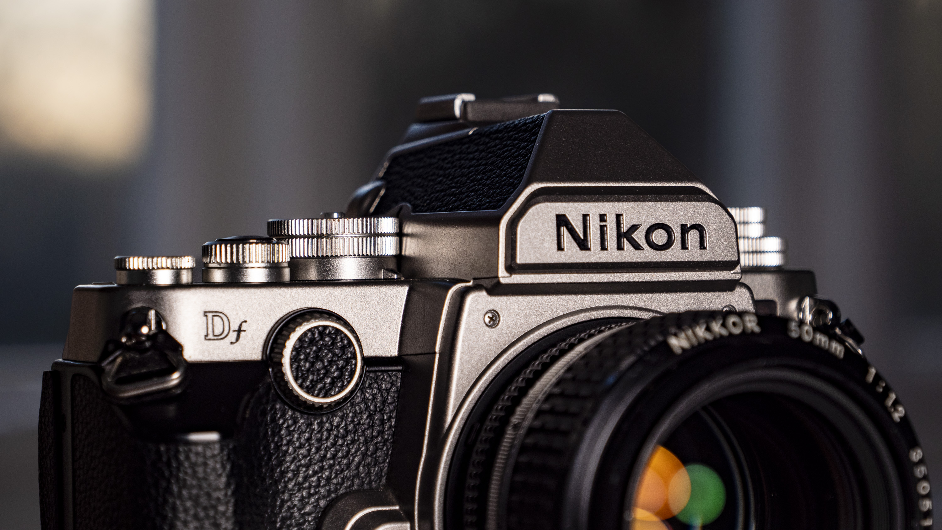 Nikon Df DSLR camera on a wooden surface by large window, with dusk light