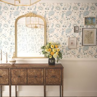 decorative blue and cream wallpaper in hallway with vintage sideboard