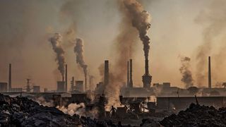 Smoke billows from a steel plant in China into a smoggy sky.