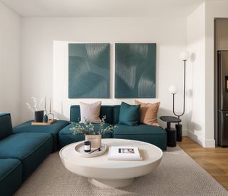 A living room with teal sofa and white walls