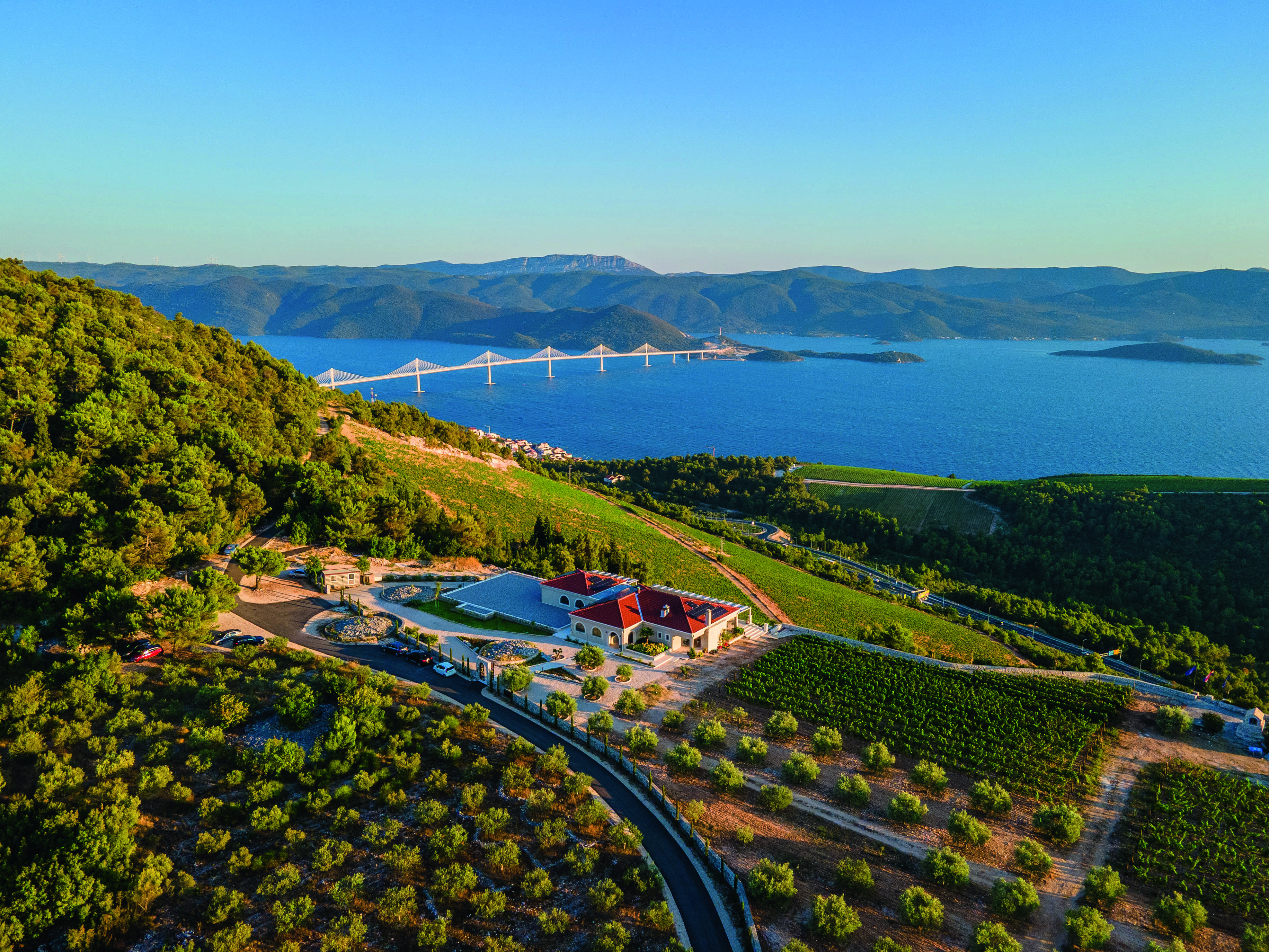 Buildings and vines at sunset, with sea and mountains in the background