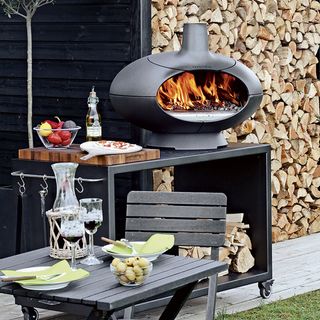 outdoor oven on black trolley and black wooden table with chair