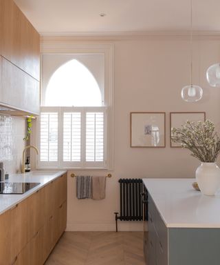 kitchen with warm white walls, wooden cabinets, parquet flooring and arched window