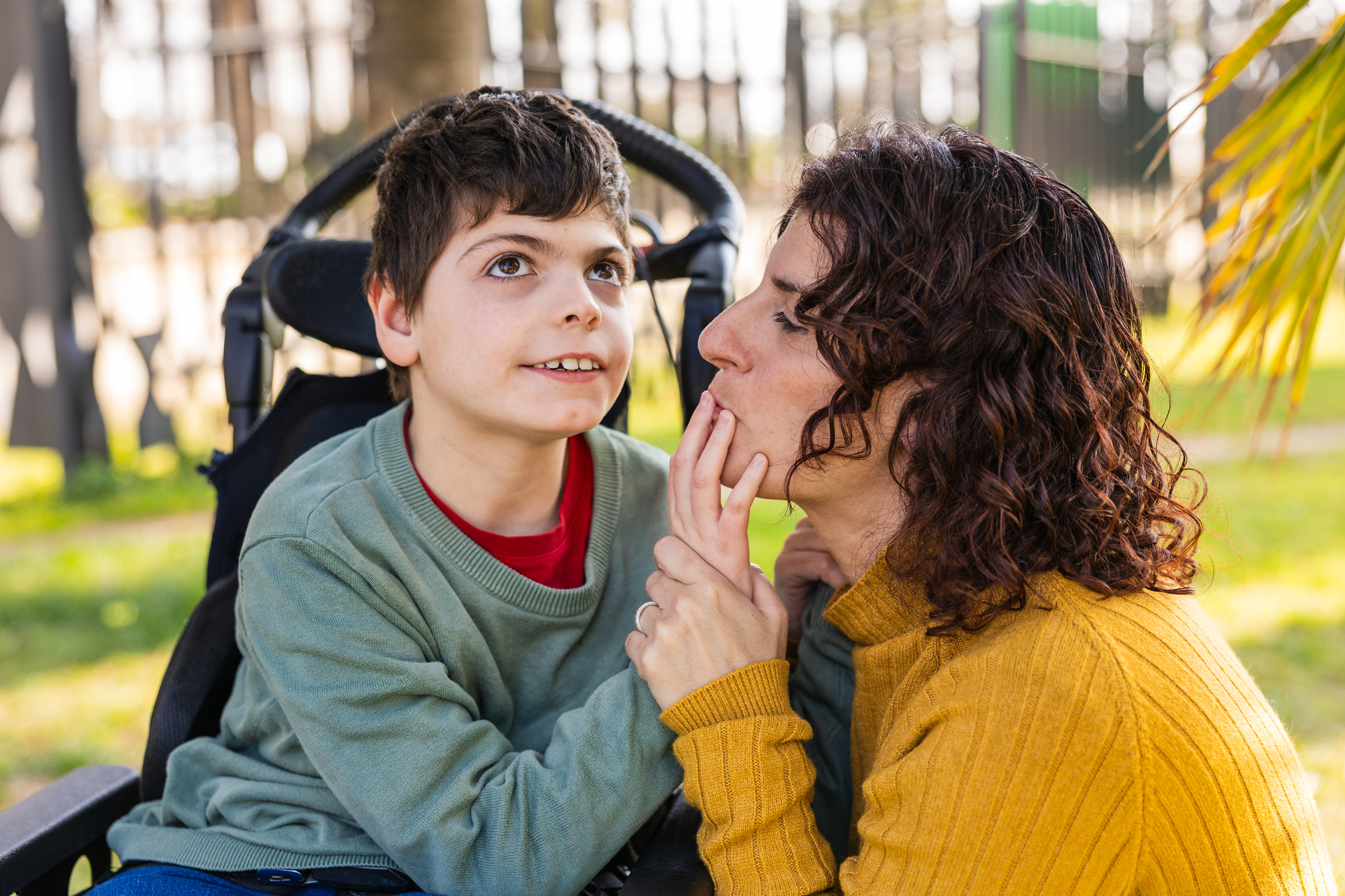 A child in a wheelchair playing with his mother