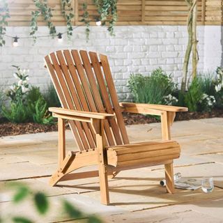 A wooden Adirondack chair on a paved patio