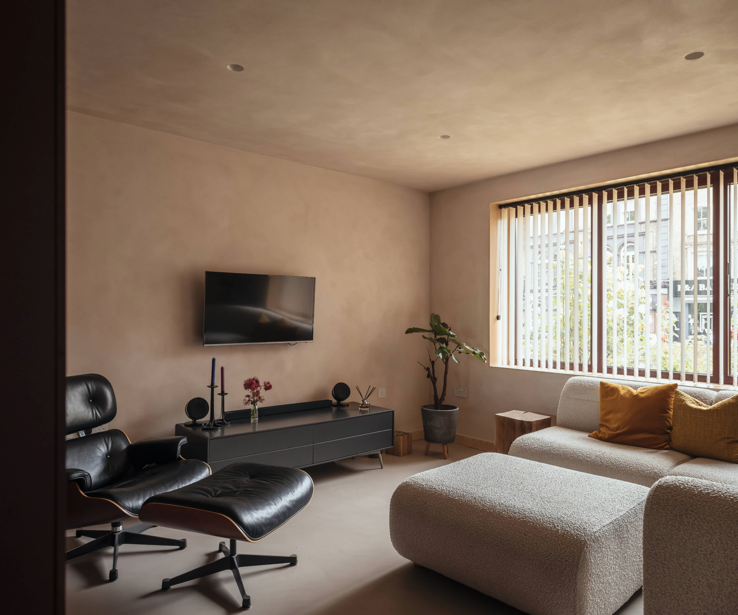 Living room with sofa, tv, leather chair and shutters