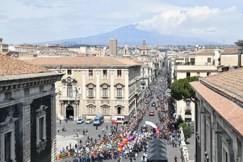 Mount Etna smokes in the background as the riders leave out of Catania