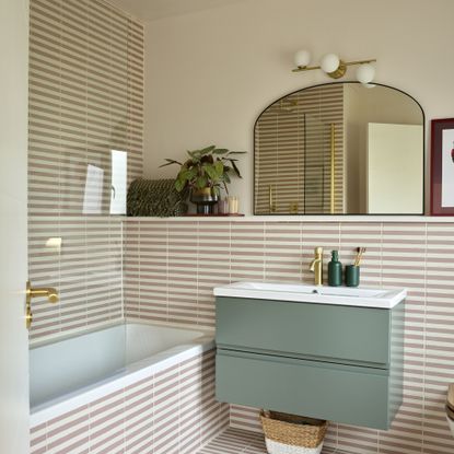 Stripy tiled bathroom with green vanity unit and mirror