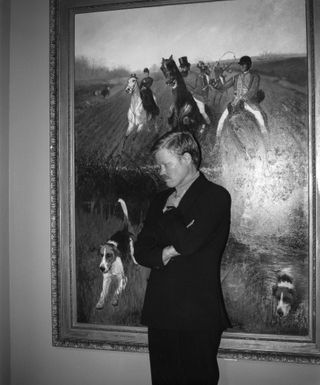 actor Jesse Plemmons standing in front of a classic painting in a suit