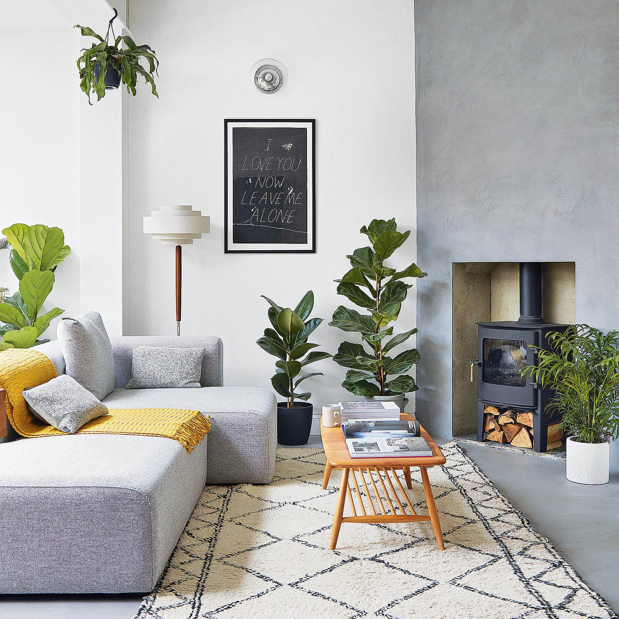 Grey living room with yellow throw, berber rug and potted plants