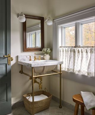 Small bathroom with open brass washstand and sheer cafe curtain