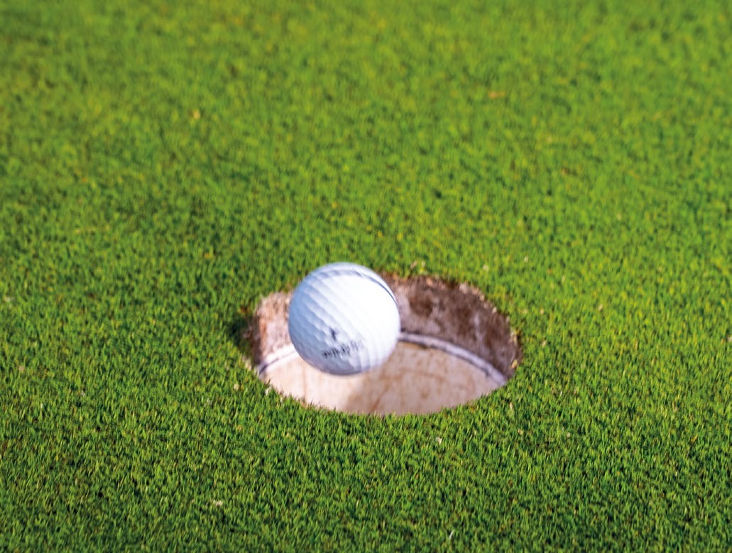 A golf ball falling into the hole after a short putt