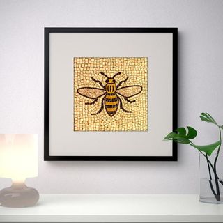 Picture of a bumble bee in black frame hanging on white wall
