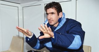 Leeds United forward Eric Cantona calms the media down as he looks on from the bench prior to making his Leeds debut as a substitute during the League Division One match between Oldham Athletic and Leeds United at Boundary Park on February 8, 1992 in Oldham, England.