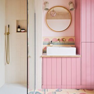 Bathoom with fitted pink storage cabinets graphic tiled flooring and splashback, a contemporary basin with mirror and shower area