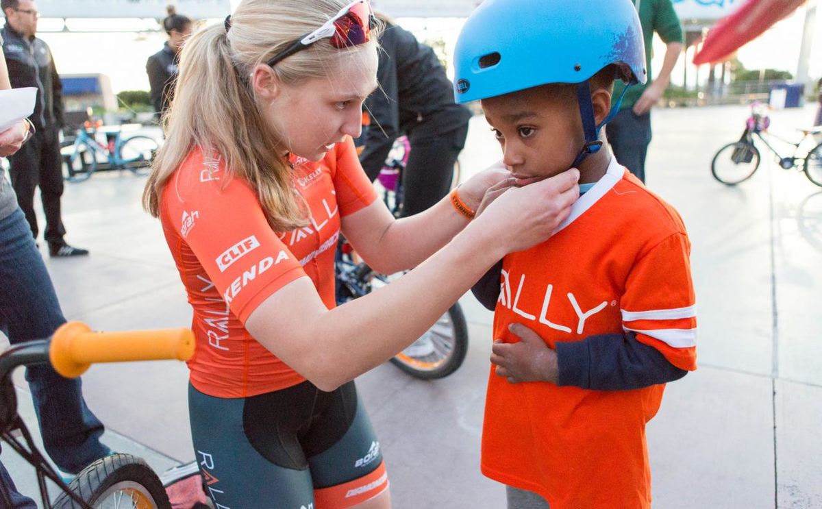 Rally Cycling's Megan Jastrab helps fit a helmet at the Rally Health bike build