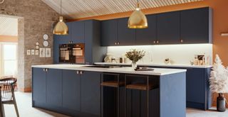 navy blue kitchen with marble worktops and an exposed brick wall with in-built seating in the large kitchen island to support key kitchen trends 2024