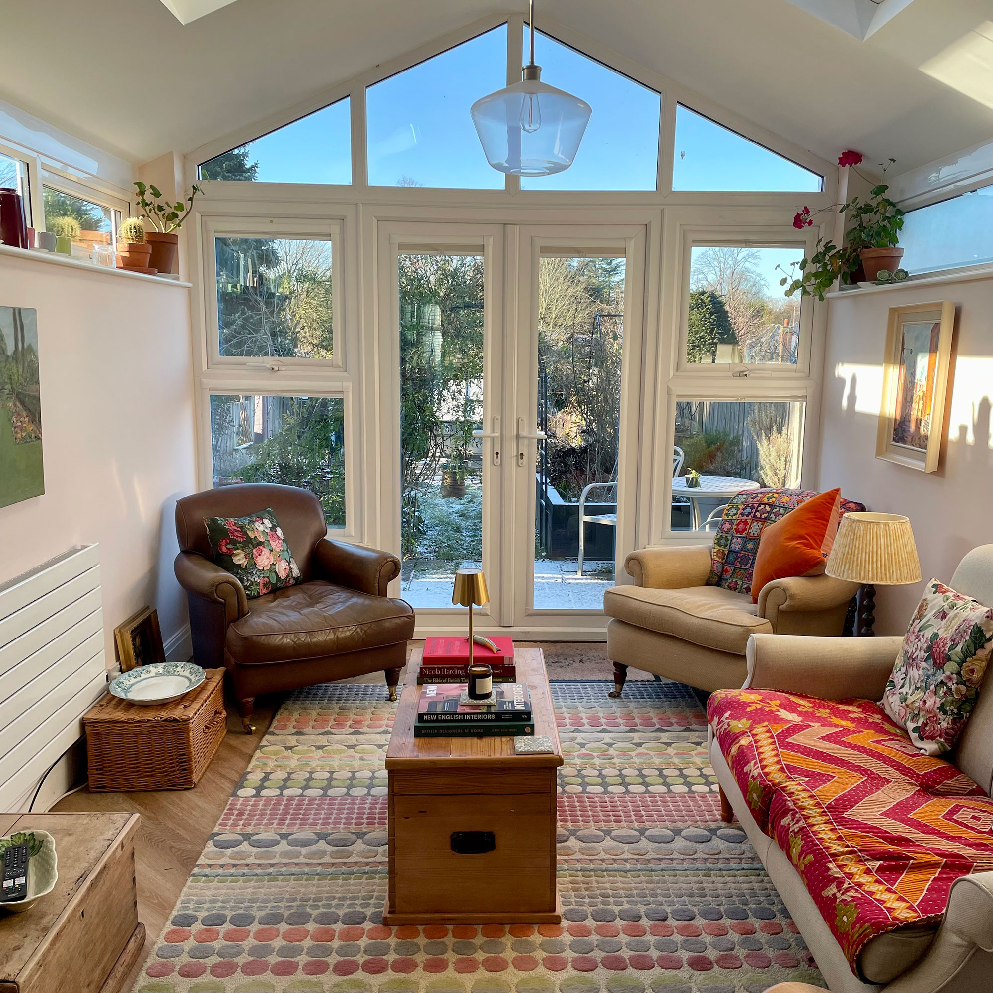 Living room with colourful rug, wooden chest coffee table and floor to ceiling glazing