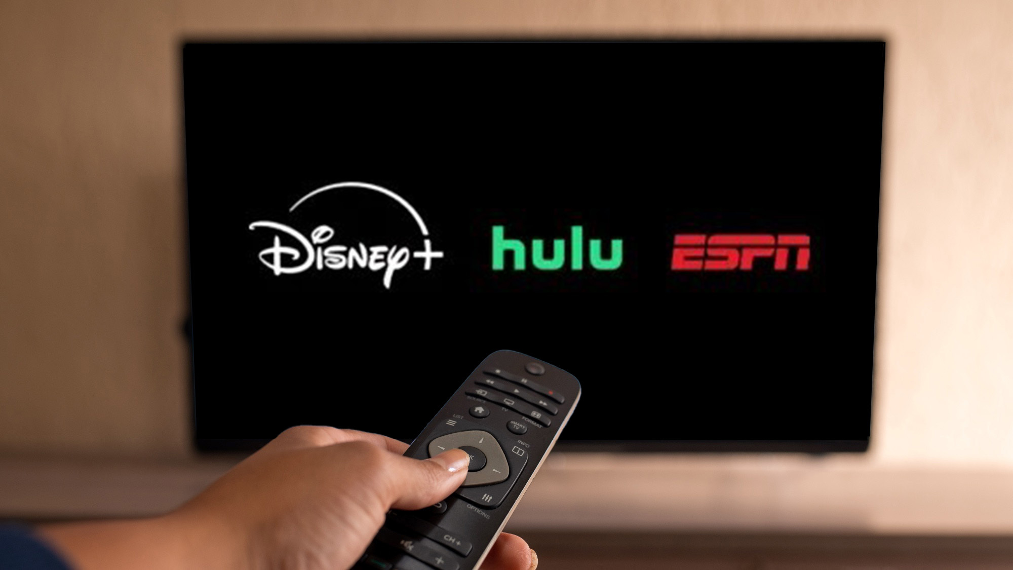 The Disney Plus, Hulu and ESPN logos superimposed on a TV screen.