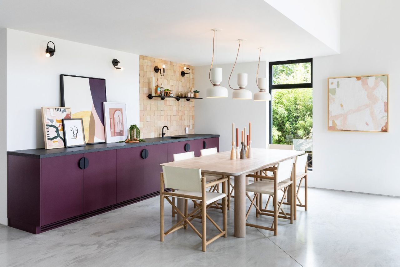 Wooden dining table and chairs in modern space with duo wall covering and decorative black sconces