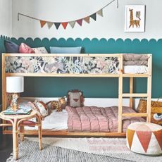 A children's room with a bunk bed and half a wall painted in a teal shade with a scalloped trim