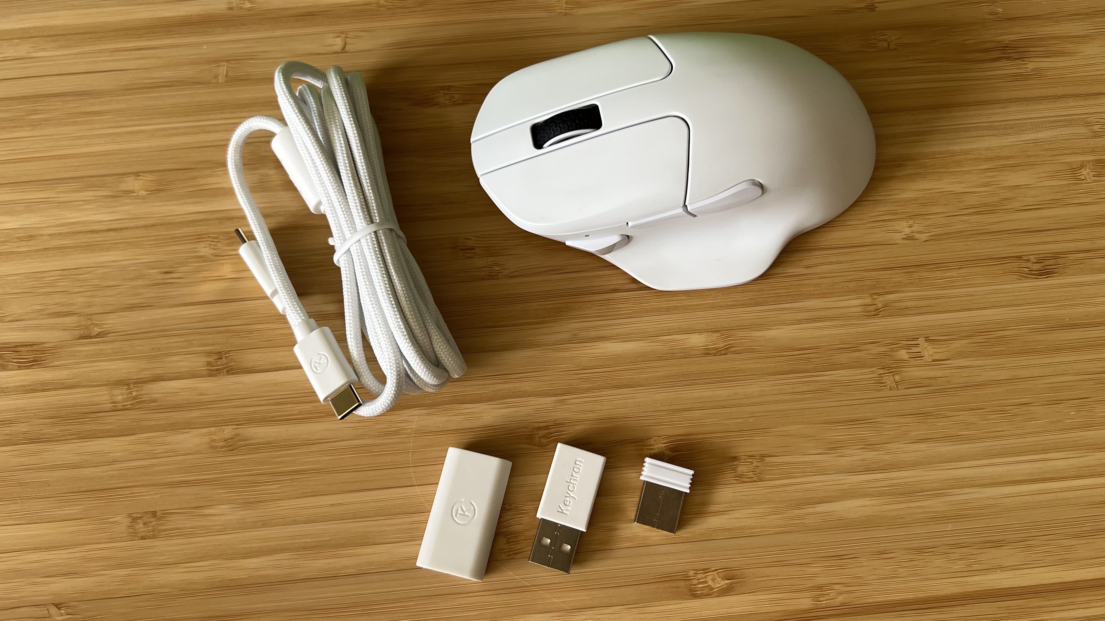 Keychron M7 8K gaming mouse with receivers and white USB-C cable on a wooden desk