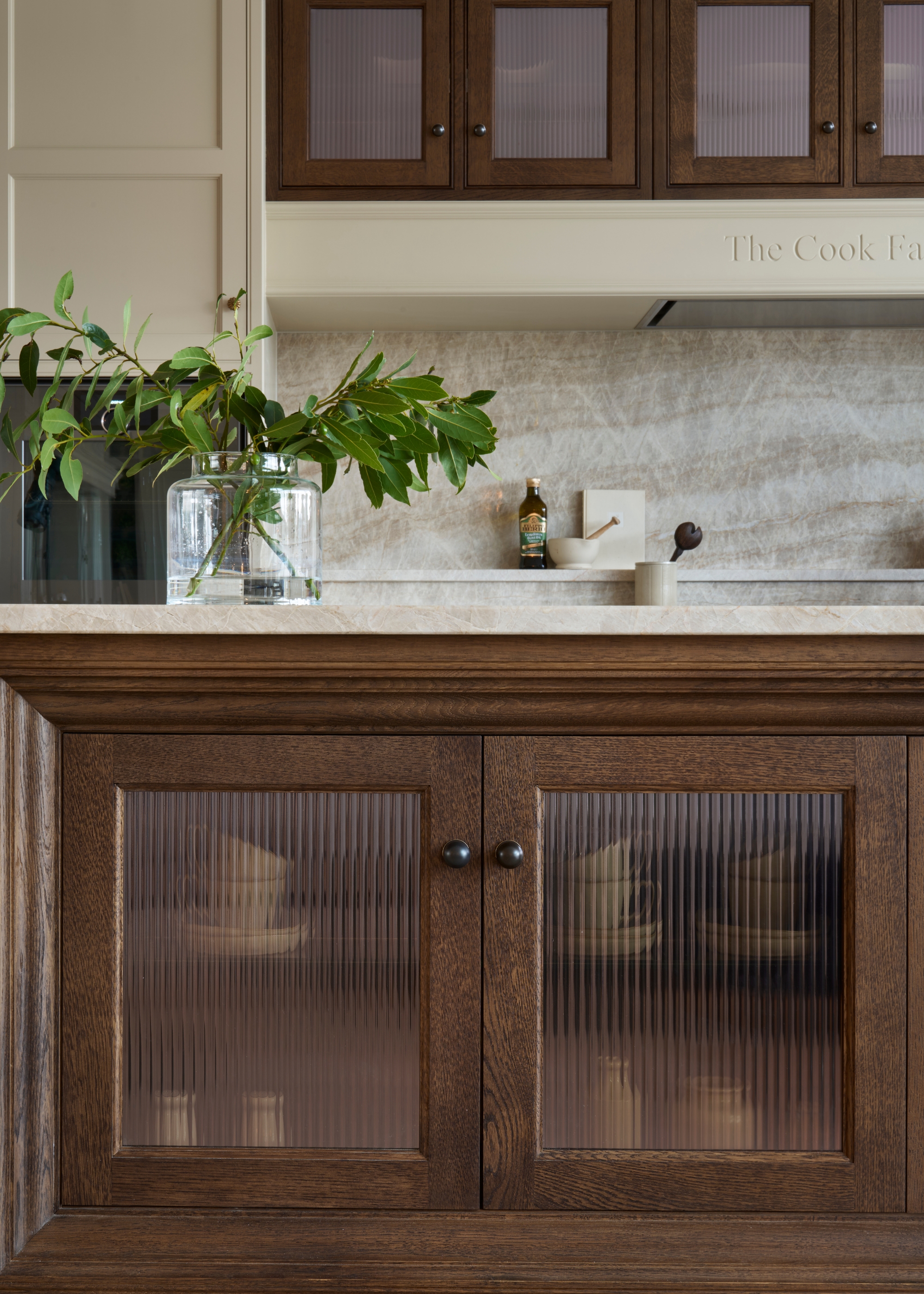 A dark wood kitchen with fluted glass and bronze hardware