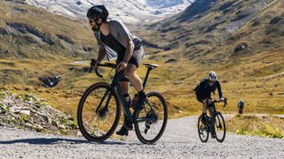 Two gravel riders climbing a hill in the mountains