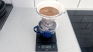 a black coffee scale by Hario is photographed in real-life usage in a kitchen