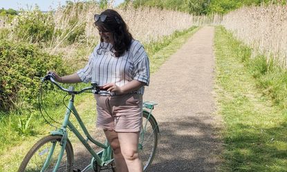 A lady in a white shirt holding a mint green bike