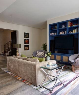 A blue painted shelving unit and cream sofa illustrating long living room ideas.