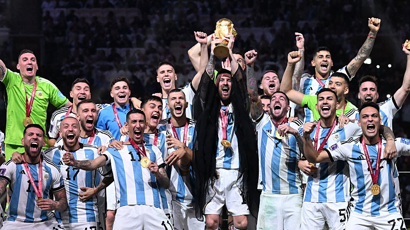 Argentina's captain Lionel Messi (C) lifts the FIFA World Cup Trophy as he celebrate with teammates winning the Qatar 2022 World Cup final.
