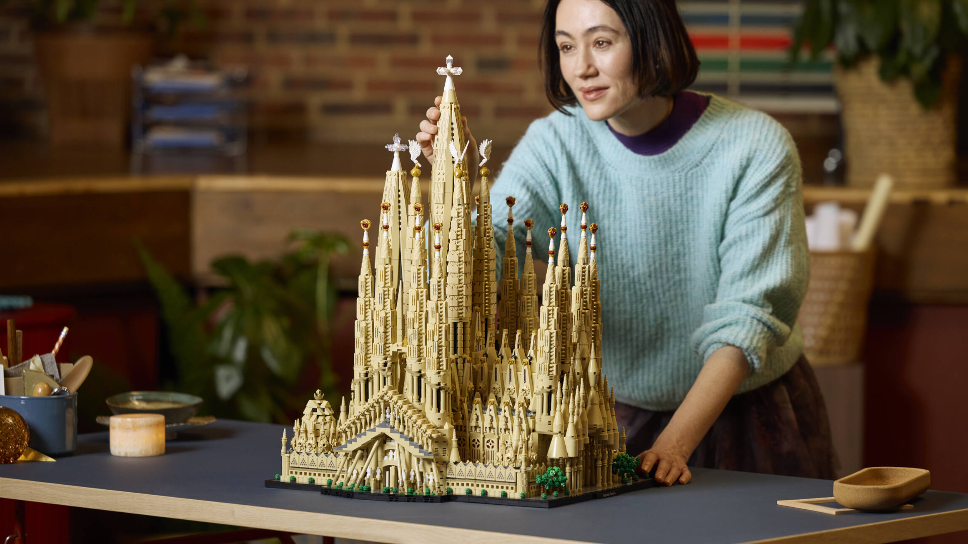 A woman looks at the Lego Sagrada Familia as she places the final tower on top of it