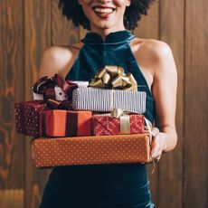 woman in halterneck velvet dress holding pile of last minute beauty gifts