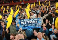 Manchester City fans hold up inflatable bananas and a banner that reads "In Khaldoon we trust"