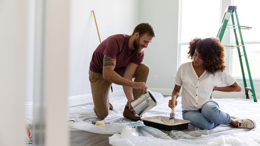 female and male in room being decorated pouring paint into tray with ladder in background
