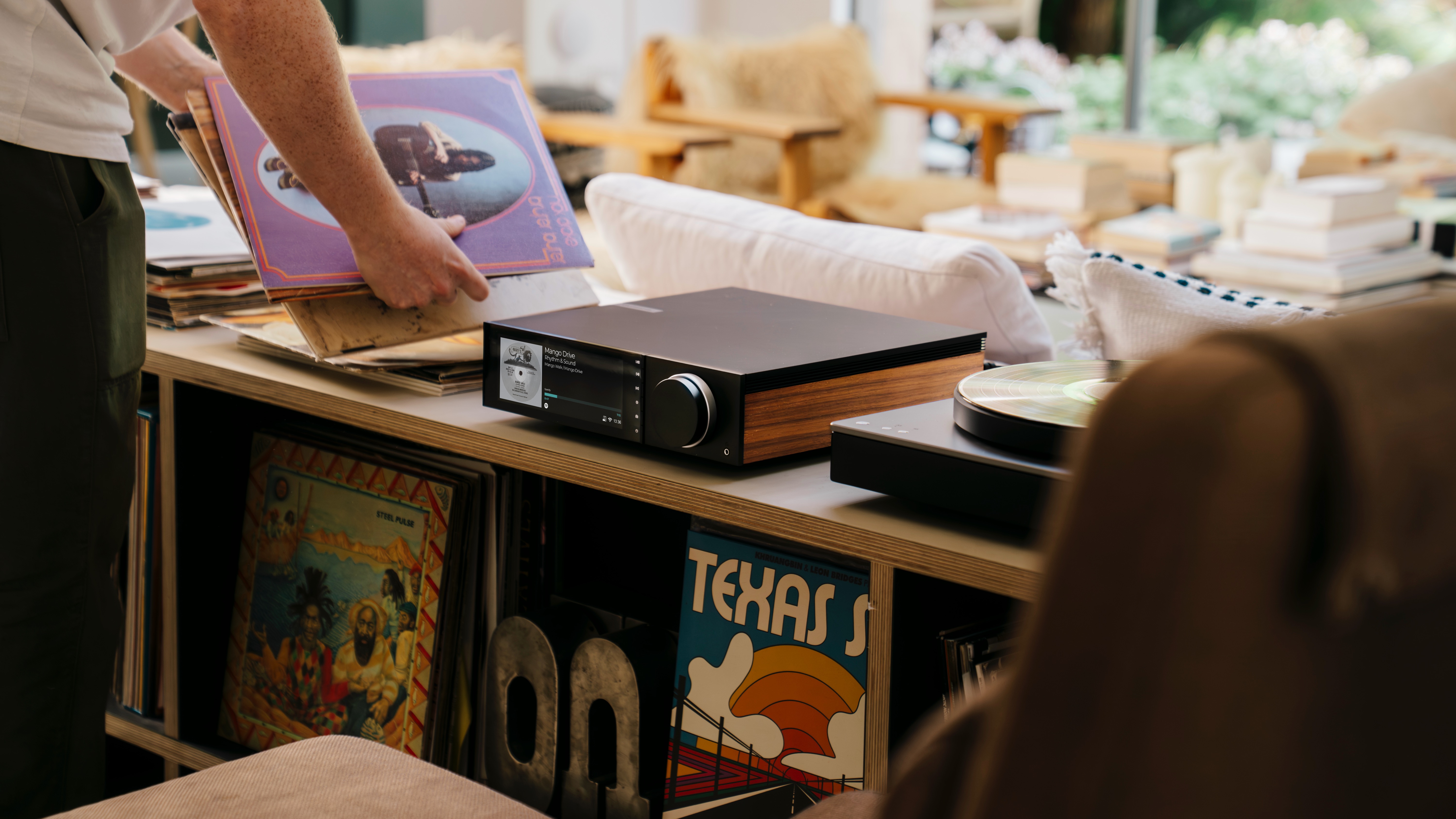 Cambridge Audio Evo 150 SE streaming amplifier in warm living room setting with vinyl records and books