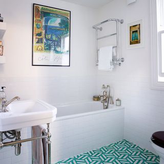 White bathroom with green chevron floor tiles and picture on wall