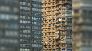 Two buildings, one shrouded in shadow, the other illuminated by sunlight