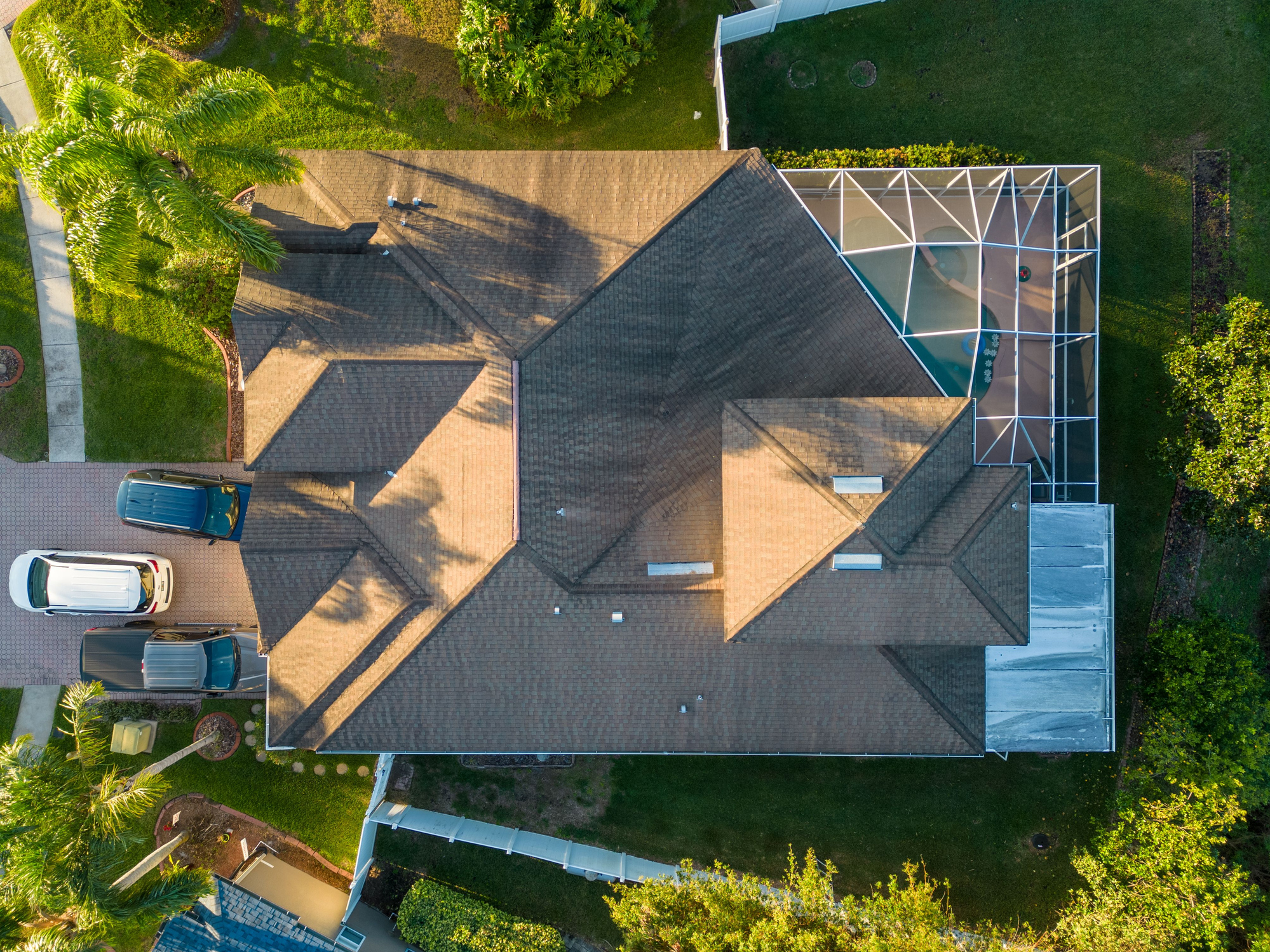 A drone shot of a modern house with a glass pool screen enclosure