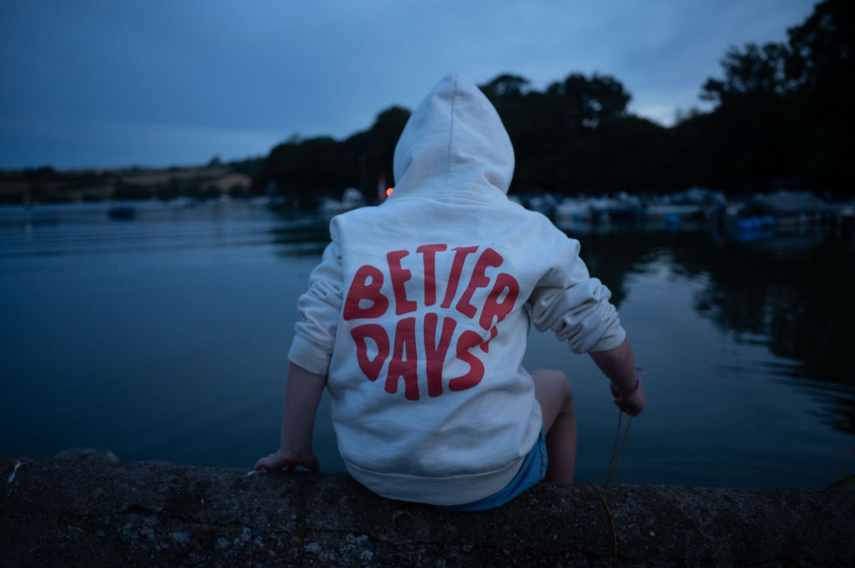 Young child wearing a hoodie side on a riverside wall, crabbing.