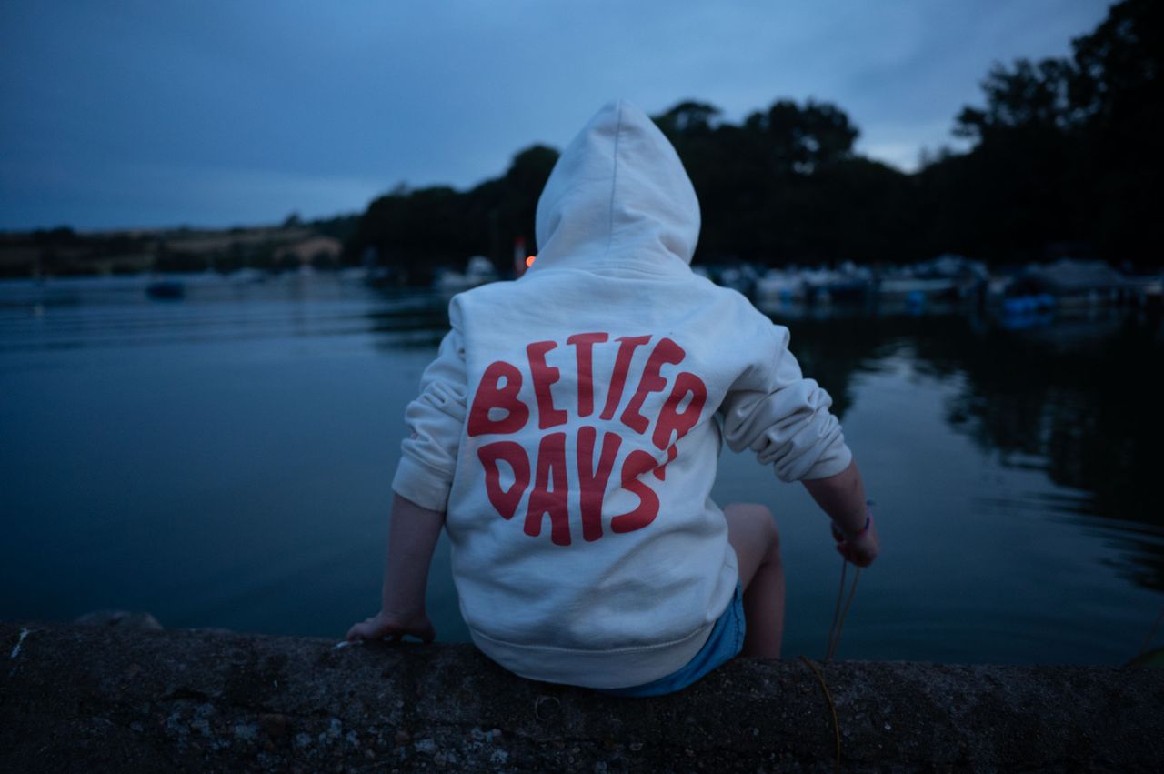 Young child wearing a hoodie side on a riverside wall, crabbing.