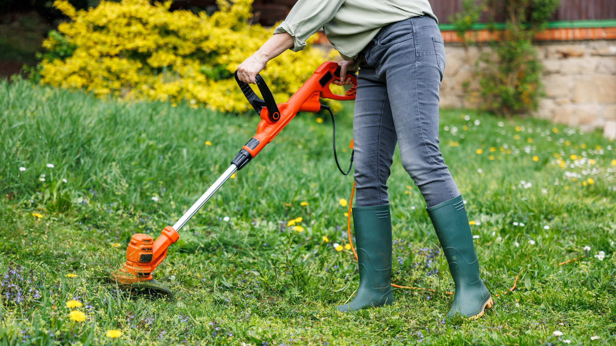 woman using string trimmer in yard