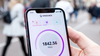 En person håller en iPhone medan den utför ett 5G-hastighetstest.